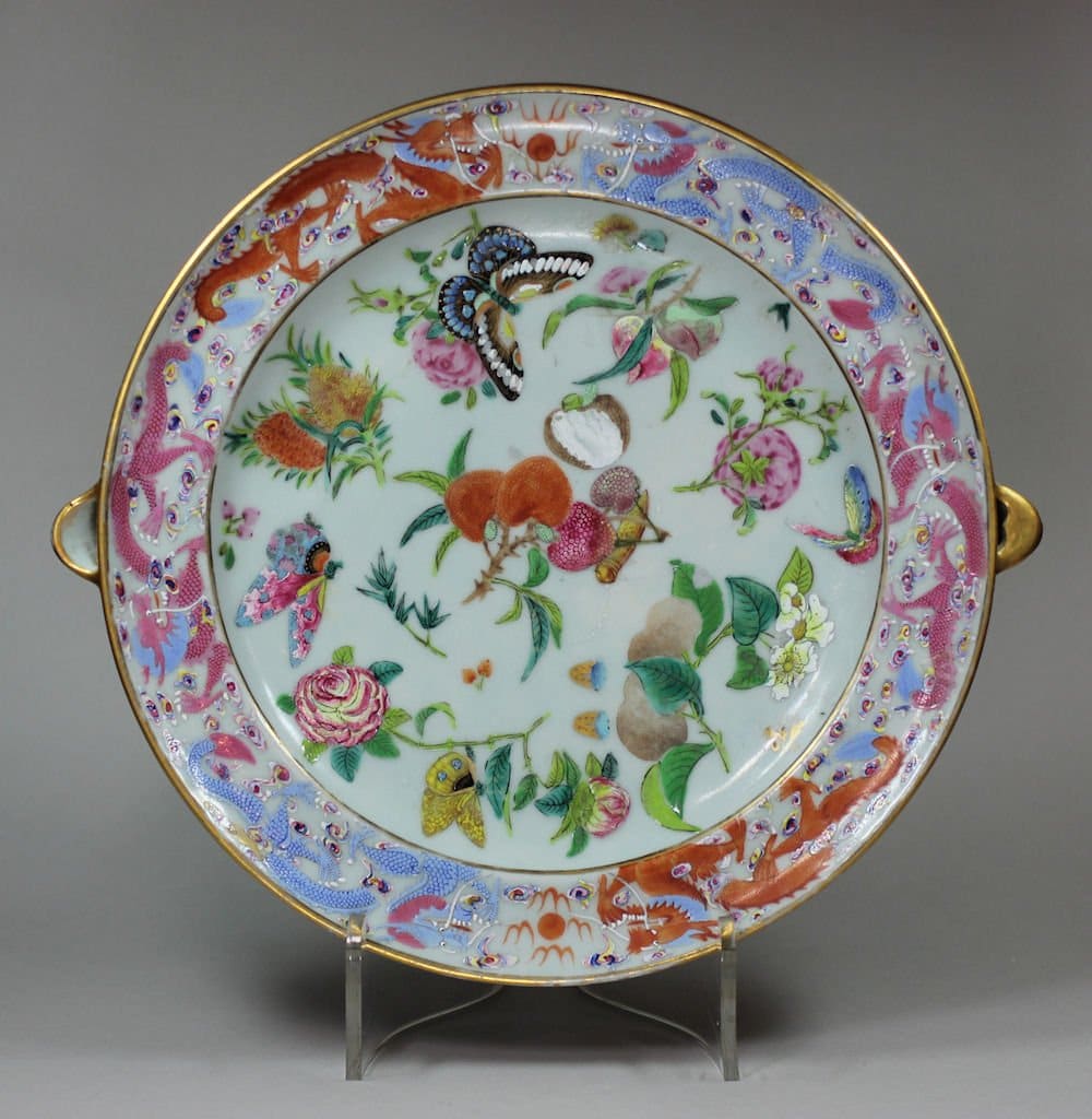 Chinese Canton warming plate, Daoguang (1821-50), Decorated with lychees, butterflies and flowers within a border of dragons chasing the flaming pearl, Diameter: 24.4cm.